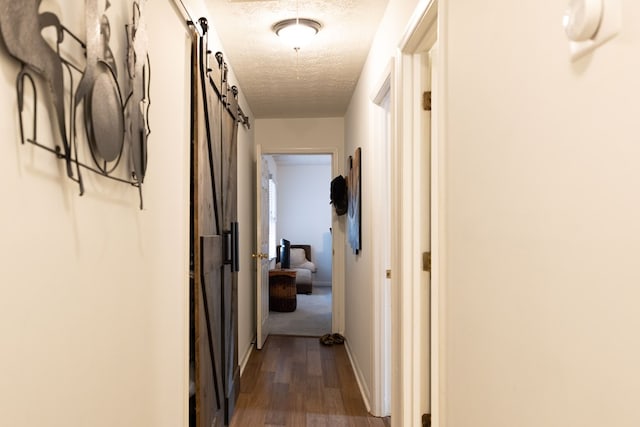 4524 Hedingham Ln, Columbus, GA 31907 - hallway featuring a textured ceiling, dark wood finished floors, and a barn door