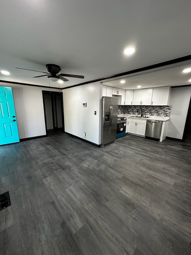 kitchen with decorative backsplash, appliances with stainless steel finishes, ceiling fan, dark wood-type flooring, and white cabinets