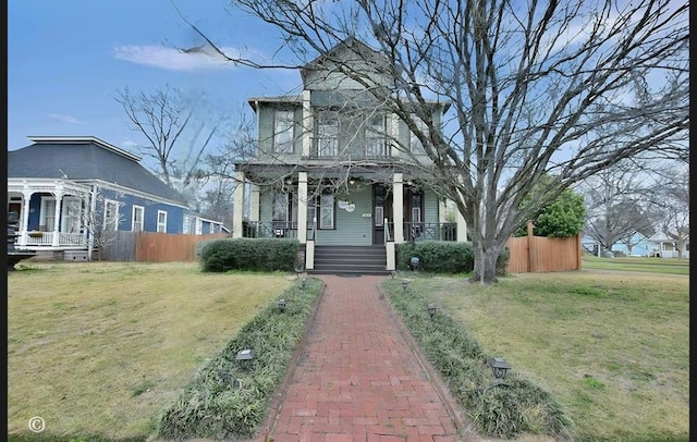 view of front of house with covered porch, a front yard, and fence