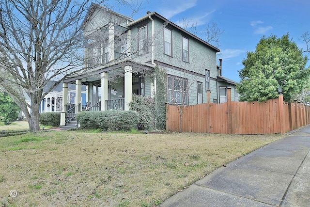 view of side of home with a lawn, a porch, and fence