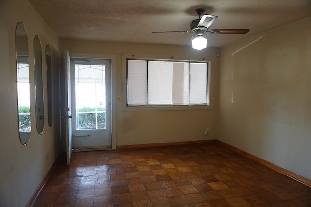 spare room with dark parquet floors and ceiling fan