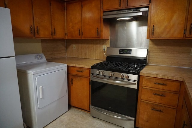 kitchen featuring backsplash, washer / dryer, stainless steel gas range oven, and white fridge