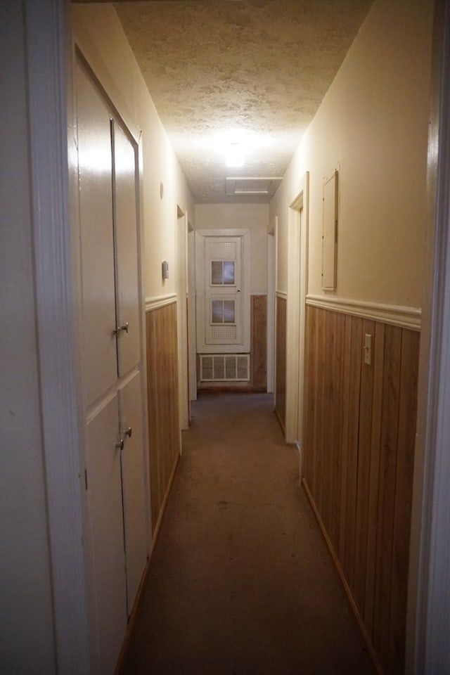 corridor with a textured ceiling and wood walls