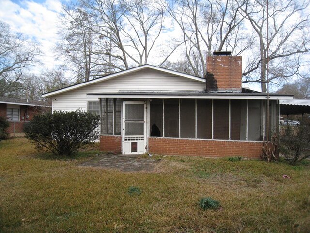 back of property with a sunroom and a lawn