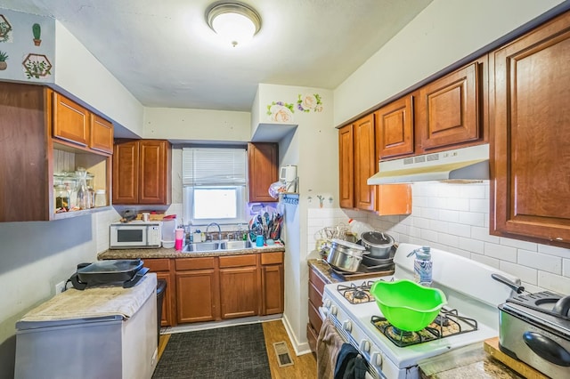 4512 Lunsford St, Columbus, GA 31903 - kitchen featuring under cabinet range hood, white appliances, decorative backsplash, and brown cabinetry