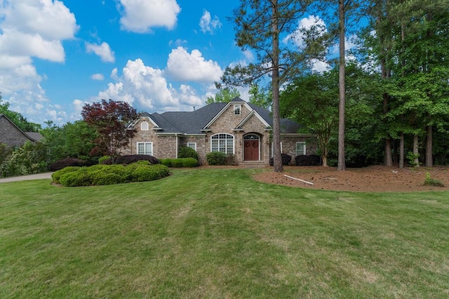 view of front of home featuring brick siding, stone siding, and a front lawn