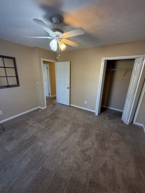 unfurnished bedroom featuring a textured ceiling, a closet, dark carpet, and ceiling fan