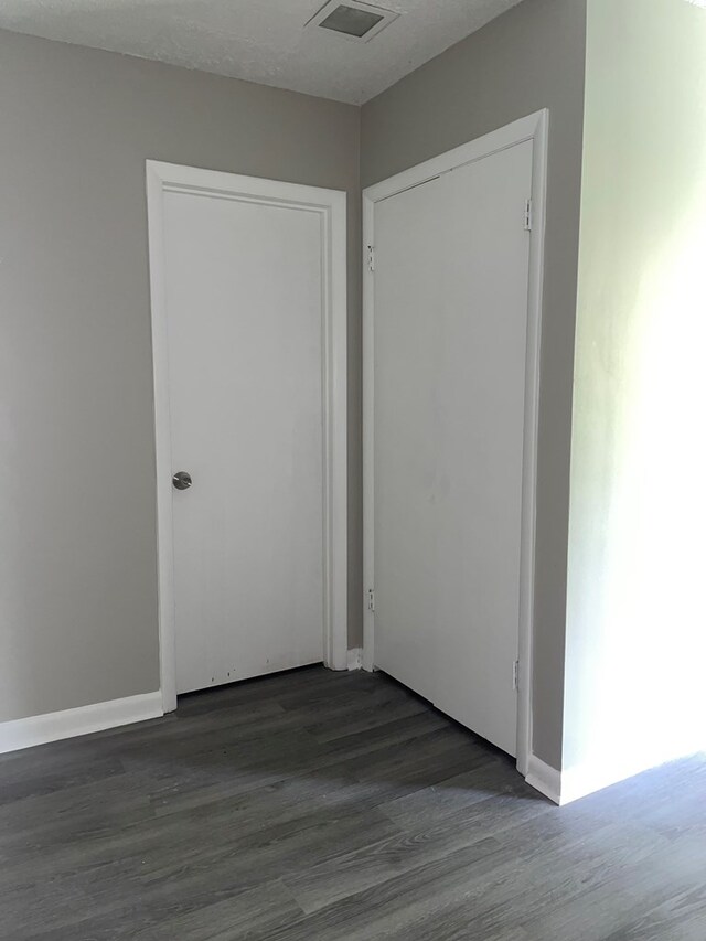 hall featuring a textured ceiling and dark hardwood / wood-style flooring