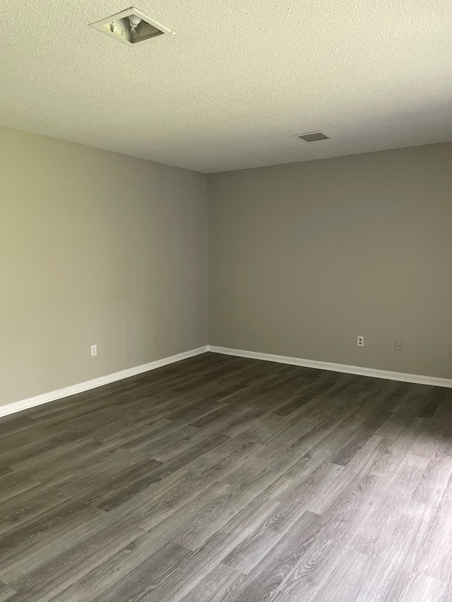 spare room with a textured ceiling and dark hardwood / wood-style floors