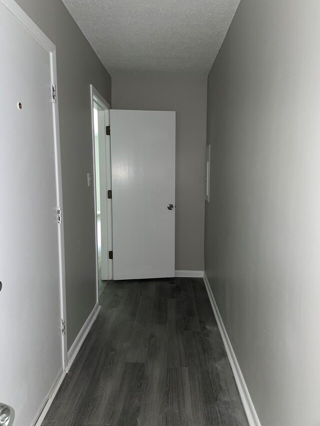 hall with dark hardwood / wood-style flooring and a textured ceiling