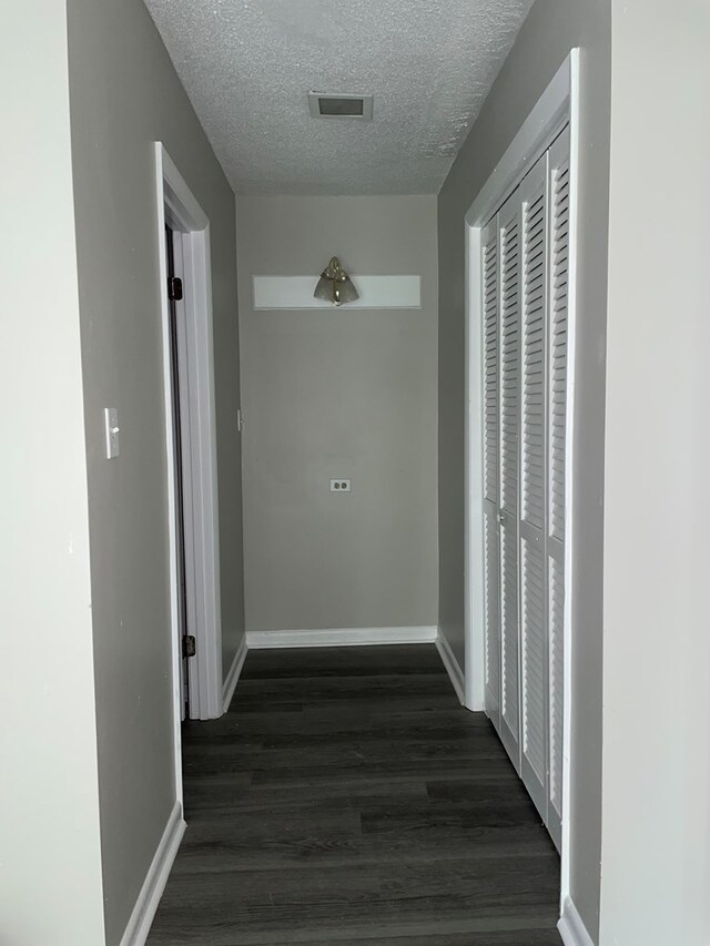 hallway featuring a textured ceiling and dark wood-type flooring