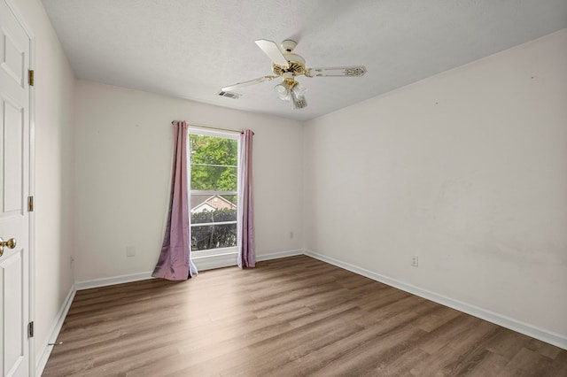 unfurnished room featuring a ceiling fan, a textured ceiling, visible vents, baseboards, and light wood-style flooring