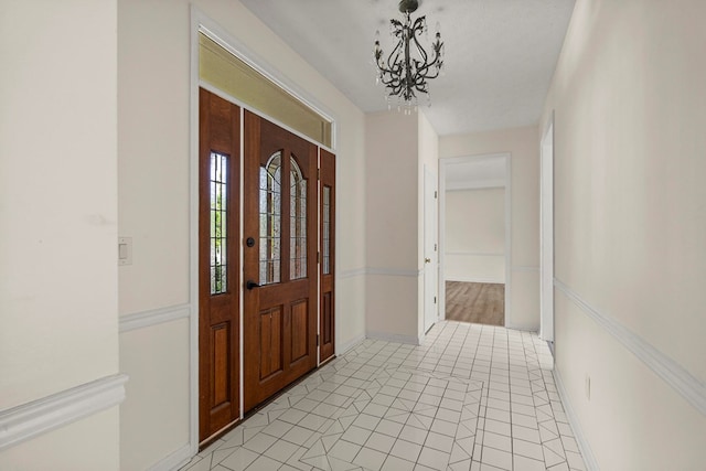 entryway featuring baseboards, light tile patterned flooring, and a notable chandelier