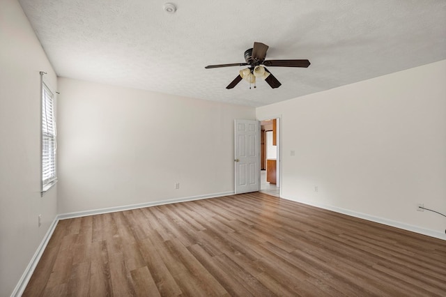 spare room with baseboards, ceiling fan, a textured ceiling, and wood finished floors
