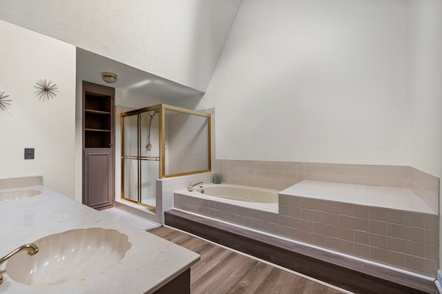full bath with a garden tub, double vanity, wood finished floors, a shower stall, and a sink