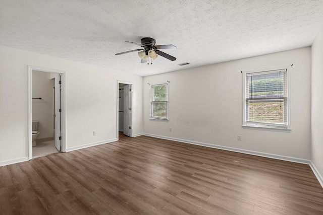 unfurnished bedroom with baseboards, visible vents, multiple windows, and wood finished floors