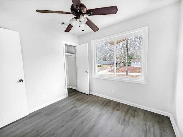 unfurnished bedroom featuring baseboards, visible vents, a ceiling fan, wood finished floors, and a closet