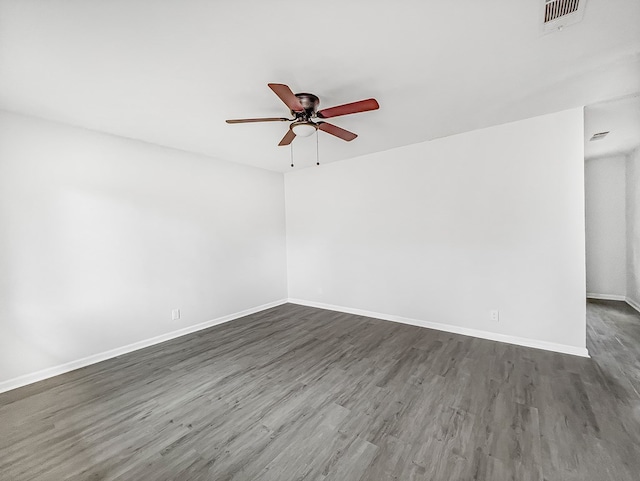 spare room featuring ceiling fan, dark wood finished floors, visible vents, and baseboards