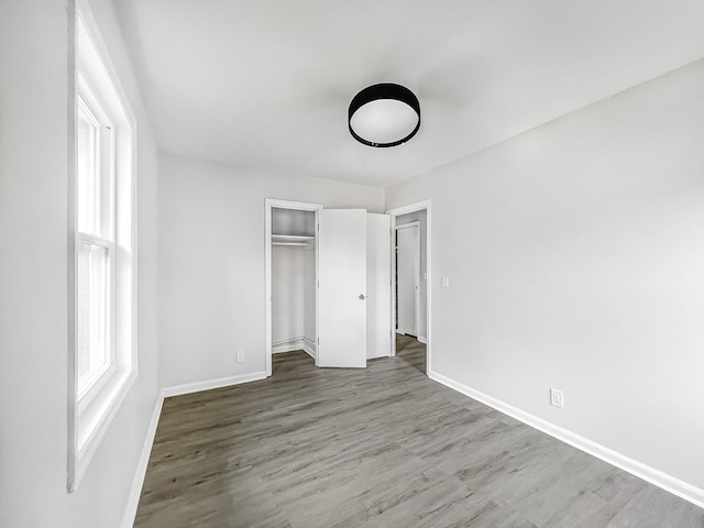 unfurnished bedroom featuring a closet, baseboards, and wood finished floors