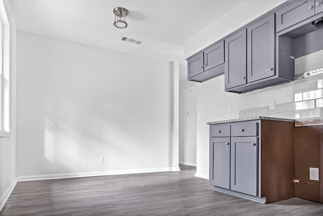 kitchen with baseboards, visible vents, gray cabinets, and dark wood finished floors