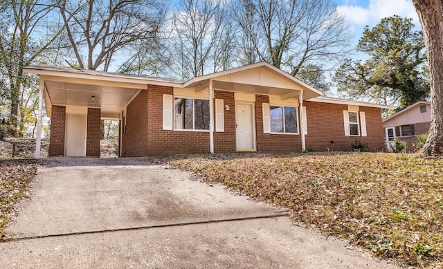 view of front facade with driveway, a carport, and brick siding