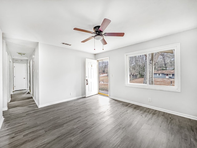 unfurnished room featuring dark wood-type flooring, a ceiling fan, visible vents, and baseboards