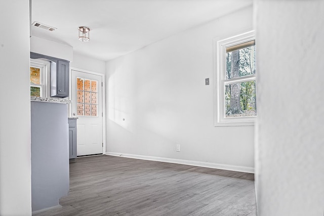 unfurnished room with dark wood-style flooring, visible vents, and baseboards