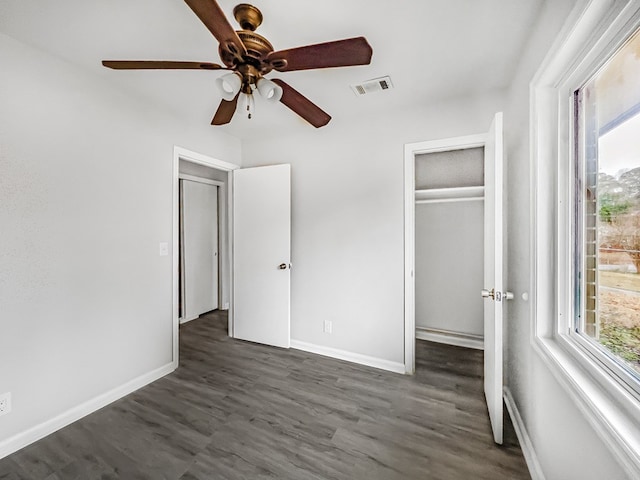 unfurnished bedroom with visible vents, dark wood finished floors, baseboards, and multiple windows