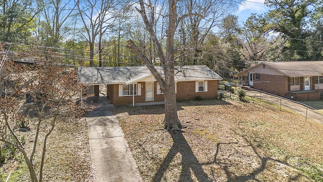 single story home with driveway, brick siding, fence, and an attached carport