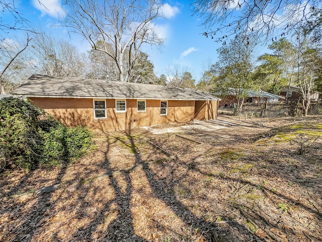 rear view of house with brick siding and fence