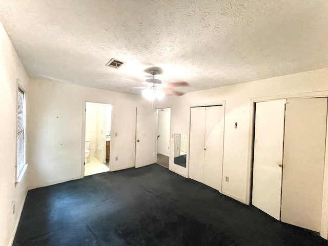4200 Curry St, Columbus, GA 31907 - unfurnished bedroom featuring two closets, a textured ceiling, dark carpet, connected bathroom, and ceiling fan