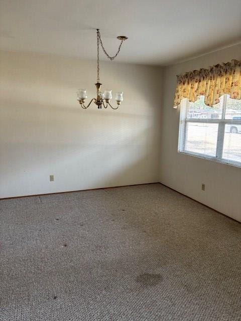 empty room with a notable chandelier and carpet