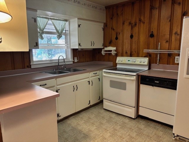 kitchen with white appliances, white cabinetry, wooden walls, and sink