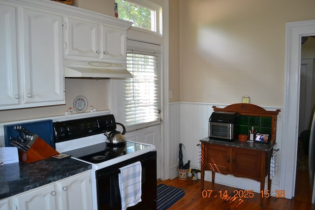 2901 Beacon Ave, Columbus, GA 31904 - kitchen featuring black electric range, a wainscoted wall, under cabinet range hood, white cabinets, and dark countertops