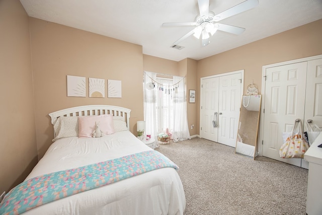 bedroom featuring a ceiling fan, visible vents, baseboards, multiple closets, and carpet flooring