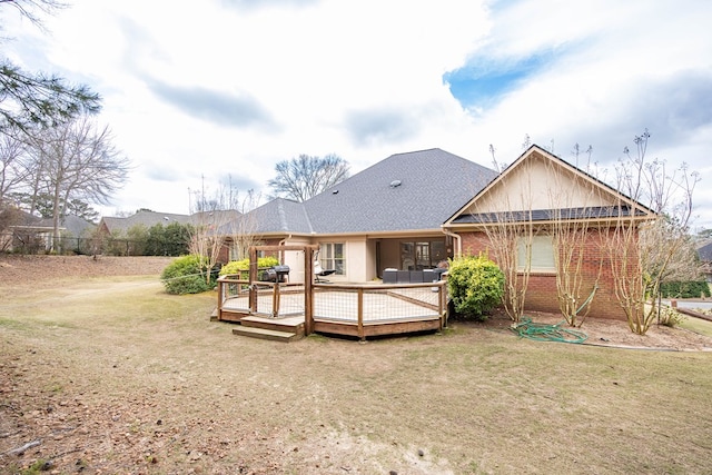 back of property with a yard, brick siding, and a wooden deck