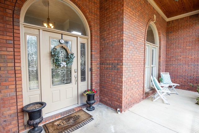 view of exterior entry featuring brick siding and a porch