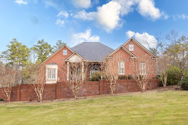 view of front facade featuring brick siding, roof with shingles, and a front yard