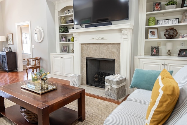 living area with built in features, a fireplace, and wood finished floors