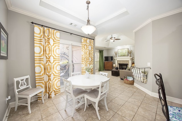 dining area featuring visible vents, baseboards, a fireplace, crown molding, and a raised ceiling