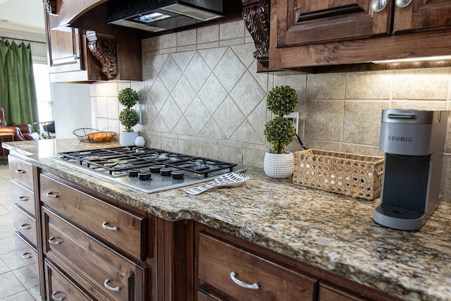 kitchen with backsplash, ventilation hood, light stone countertops, light tile patterned floors, and stainless steel gas stovetop