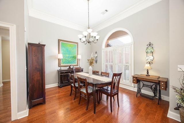 dining area with hardwood / wood-style floors, baseboards, visible vents, an inviting chandelier, and ornamental molding