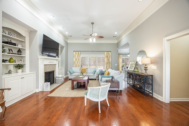 living area with built in shelves, a fireplace with flush hearth, ornamental molding, a ceiling fan, and wood finished floors