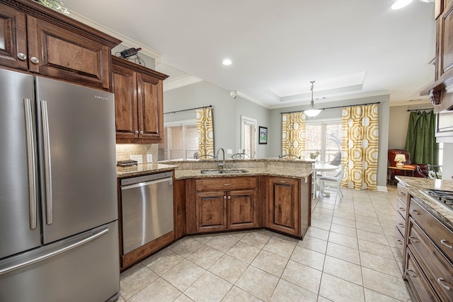 kitchen with crown molding, appliances with stainless steel finishes, a peninsula, a raised ceiling, and a sink