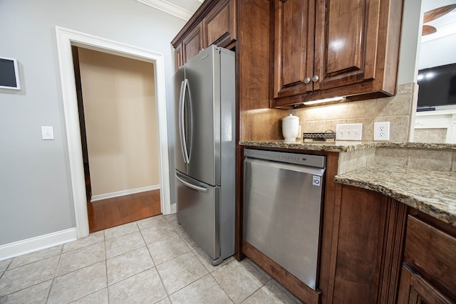 kitchen with light tile patterned floors, baseboards, stone countertops, appliances with stainless steel finishes, and tasteful backsplash