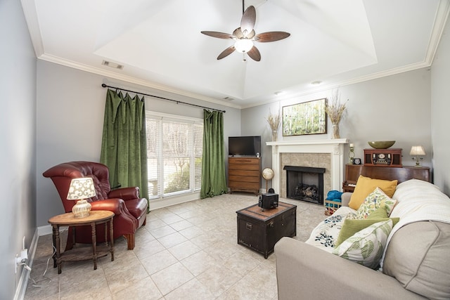 living room featuring a tiled fireplace, visible vents, a raised ceiling, and ceiling fan