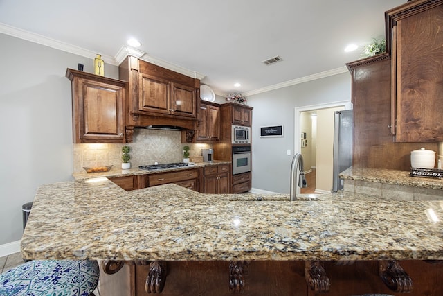 kitchen with visible vents, a peninsula, stainless steel appliances, and a sink