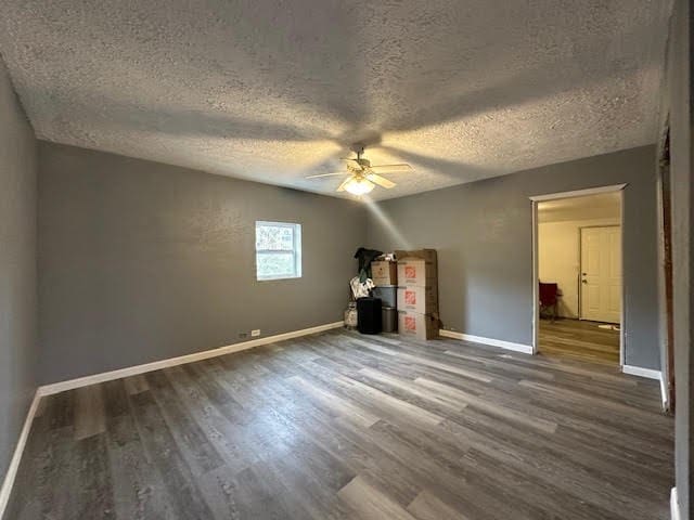 unfurnished bedroom with a ceiling fan, a textured ceiling, baseboards, and wood finished floors