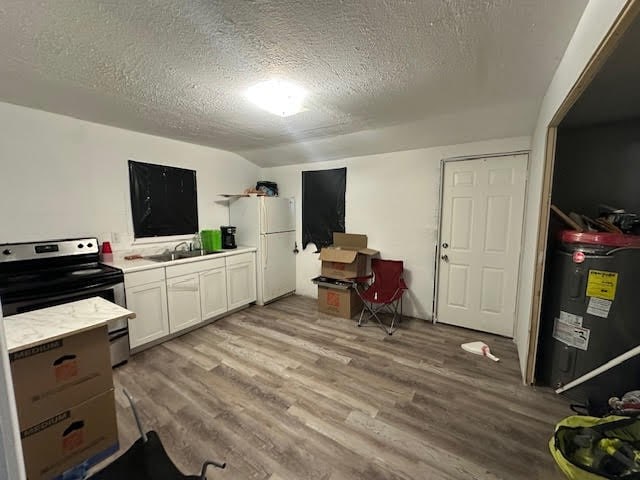 interior space with electric water heater, a sink, light wood-style flooring, and a textured ceiling
