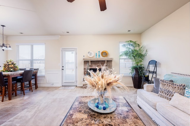 living room featuring ceiling fan with notable chandelier and a fireplace